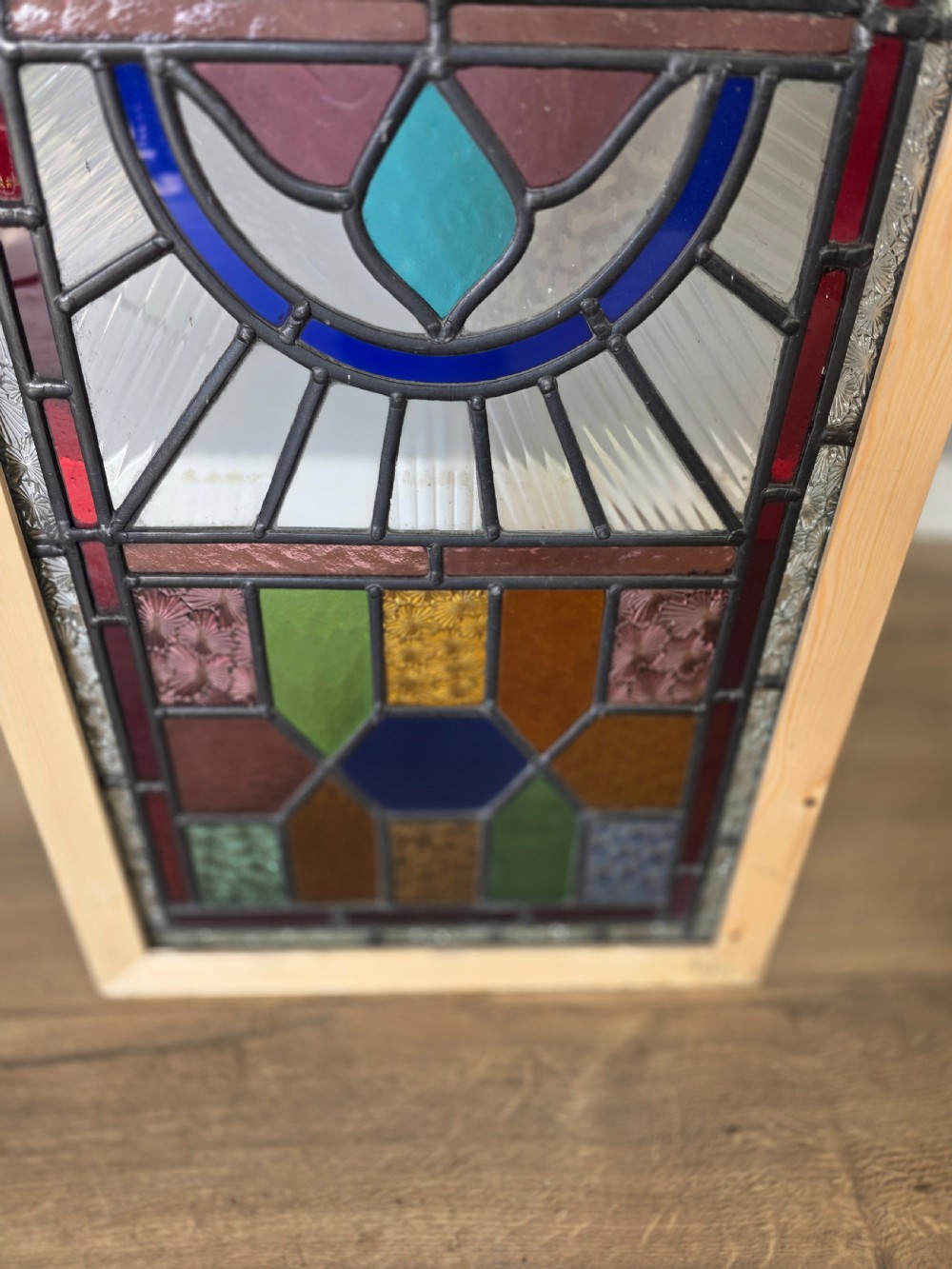 An elongated rectangular leaded glass panel featuring a central hand-painted landscape scene surrounded by geometric coloured glass borders. View V