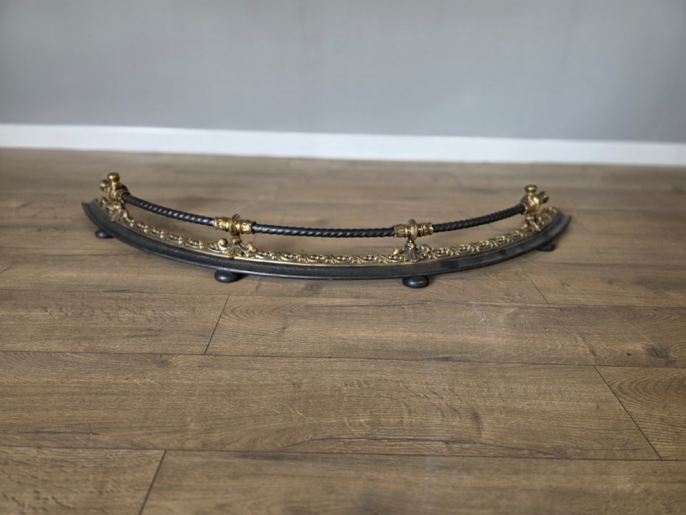 A 19th-century curved fire fender with a twisted black iron top rail and cast bronze foliate decoration. View IV