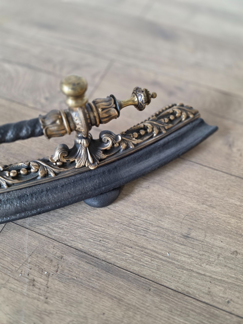 A 19th-century curved fire fender with a twisted black iron top rail and cast bronze foliate decoration. View IX