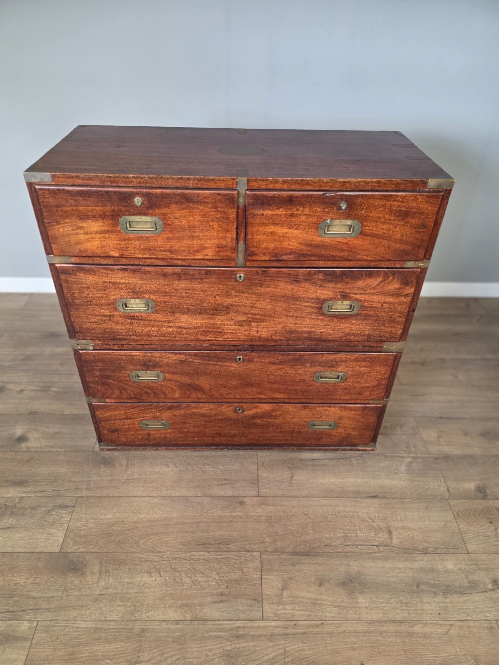 An 1830s Regency teak military campaign chest of drawers with flush brass corner brackets, strapwork, keyholes, and inset handles. View III