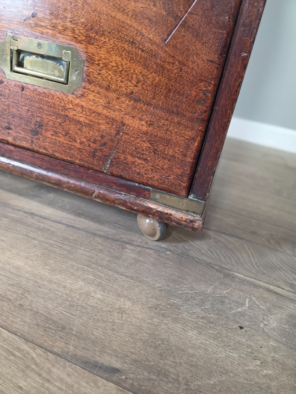 An 1830s Regency teak military campaign chest of drawers with flush brass corner brackets, strapwork, keyholes, and inset handles. View XVI