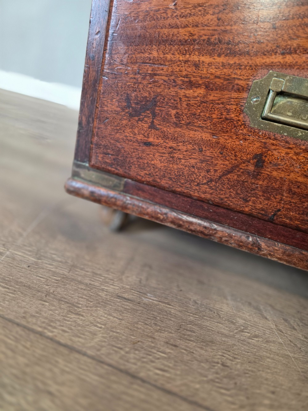 An 1830s Regency teak military campaign chest of drawers with flush brass corner brackets, strapwork, keyholes, and inset handles. View XVII