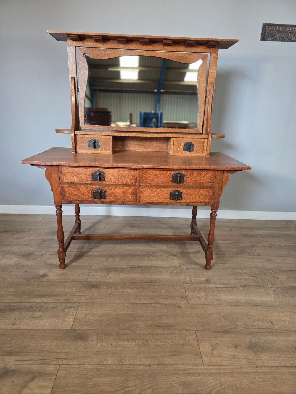 An Arts and Crafts solid oak dressing table featuring an upper mirror superstructure with side trinket drawers above a lower four-drawer chest with dark metal handles. View II
