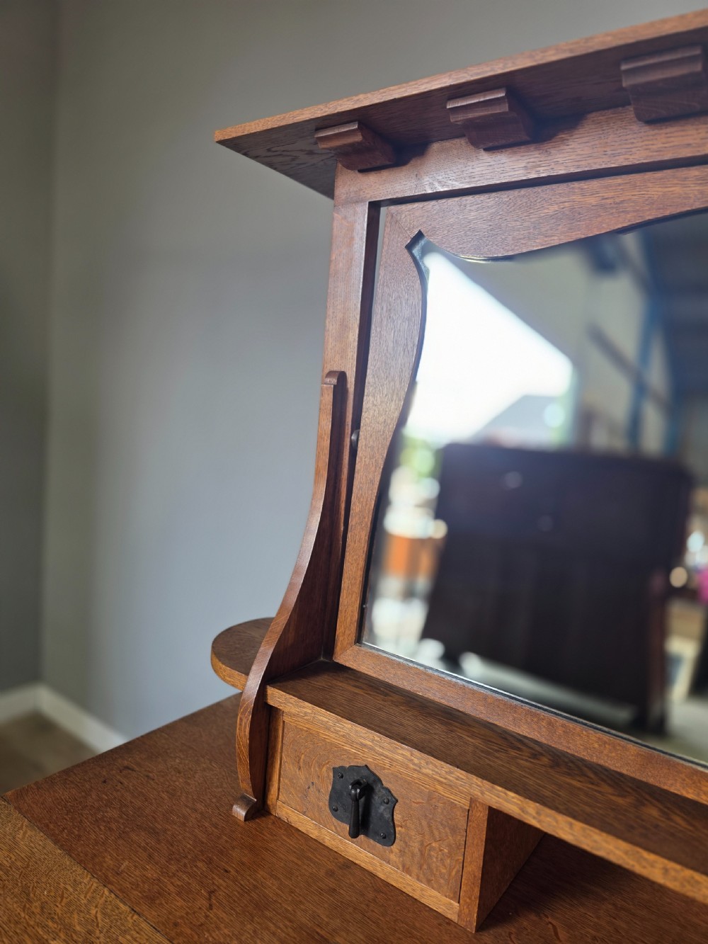 An Arts and Crafts solid oak dressing table featuring an upper mirror superstructure with side trinket drawers above a lower four-drawer chest with dark metal handles. View X