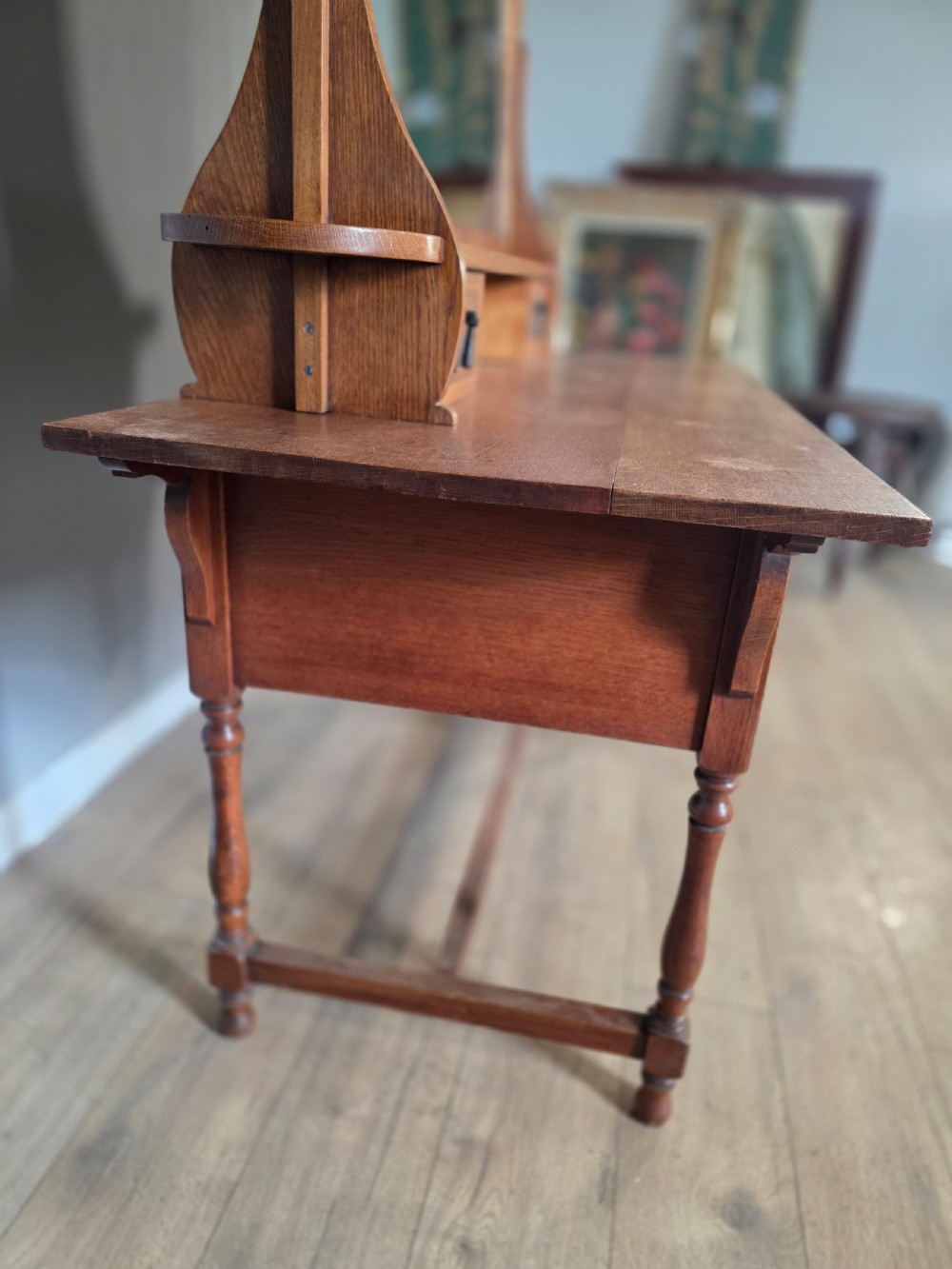 An Arts and Crafts solid oak dressing table featuring an upper mirror superstructure with side trinket drawers above a lower four-drawer chest with dark metal handles. View XII