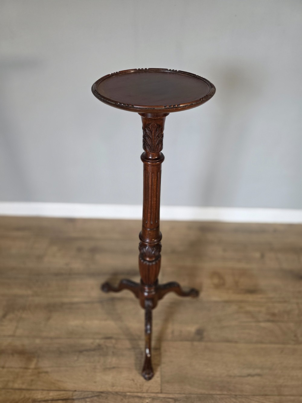An antique dark mahogany Edwardian torchere plant stand with a circular top, fluted column, and tripod cabriole legs. View II