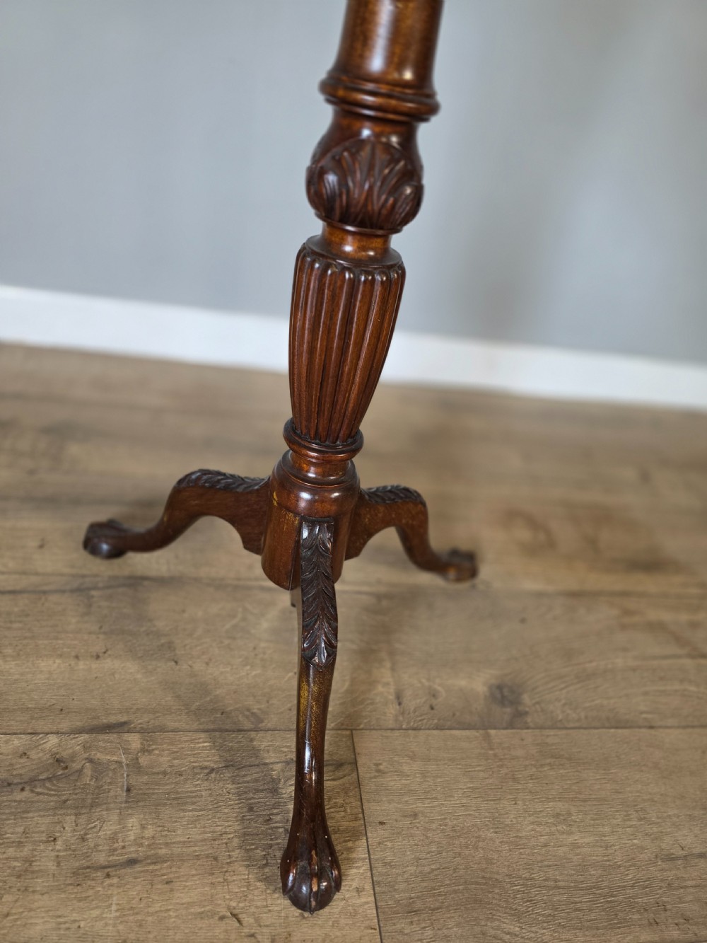 An antique dark mahogany Edwardian torchere plant stand with a circular top, fluted column, and tripod cabriole legs. View III