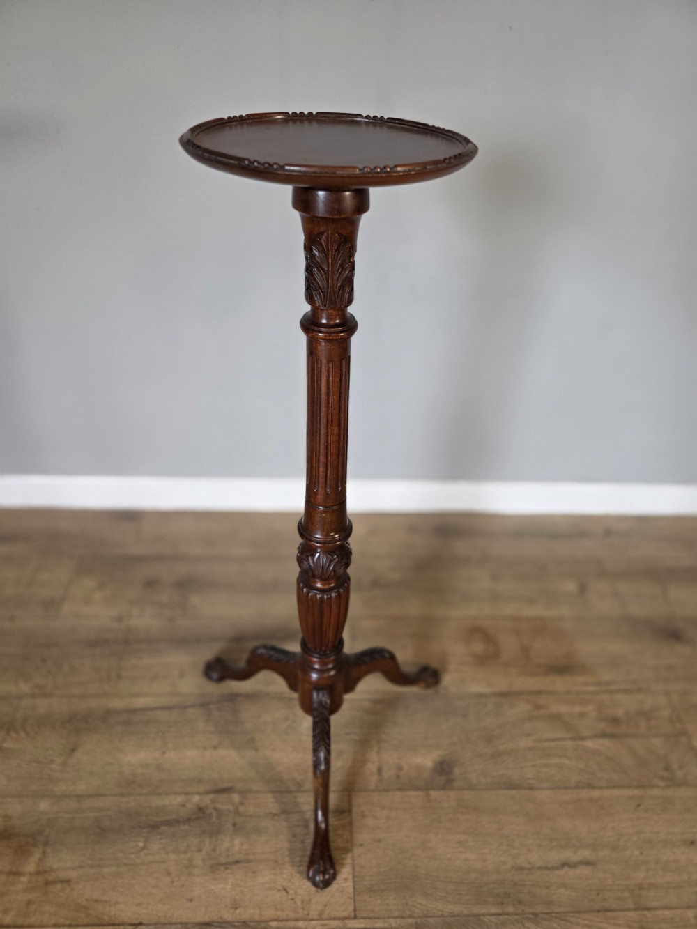An antique dark mahogany Edwardian torchere plant stand with a circular top, fluted column, and tripod cabriole legs. View V