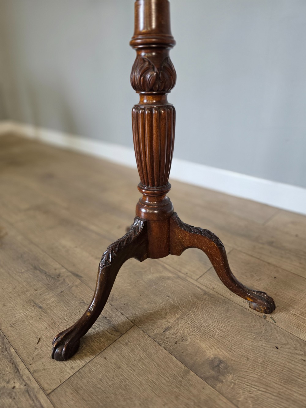 An antique dark mahogany Edwardian torchere plant stand with a circular top, fluted column, and tripod cabriole legs. View VII