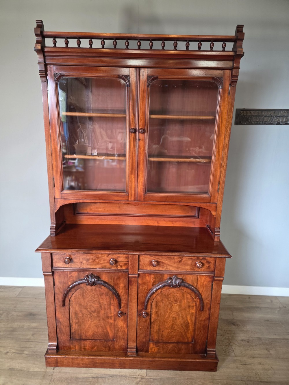 A Victorian mahogany glazed bookcase featuring a top spindle gallery, two glass cabinet doors, two drawers, and a lower double door cupboard on a plinth base. View III