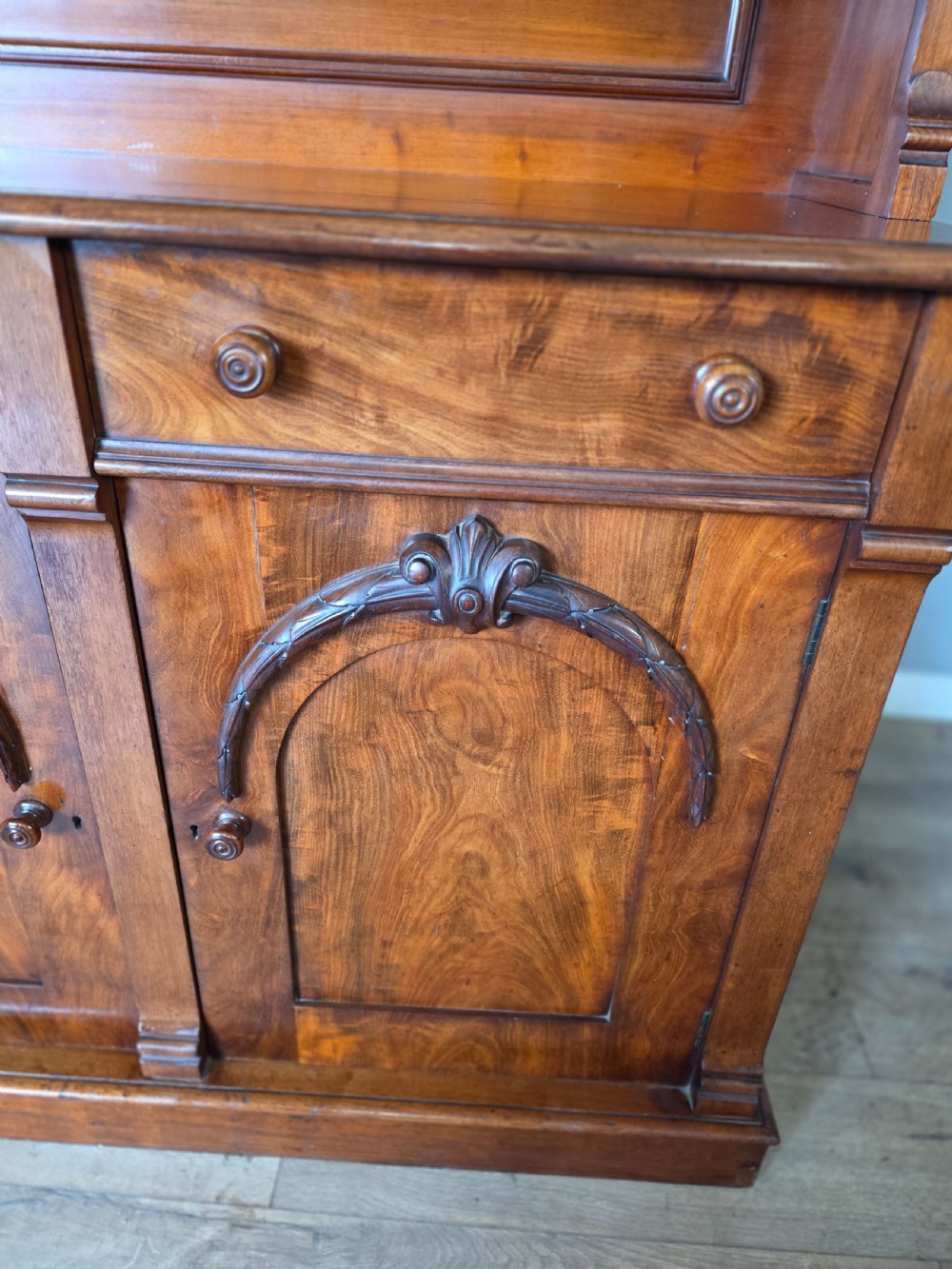 A Victorian mahogany glazed bookcase featuring a top spindle gallery, two glass cabinet doors, two drawers, and a lower double door cupboard on a plinth base. View VII