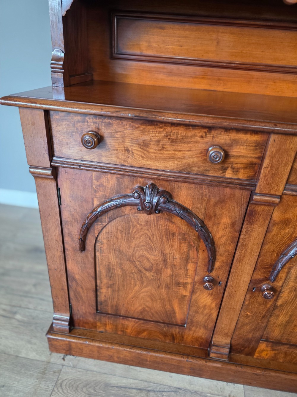 A Victorian mahogany glazed bookcase featuring a top spindle gallery, two glass cabinet doors, two drawers, and a lower double door cupboard on a plinth base. View VIII