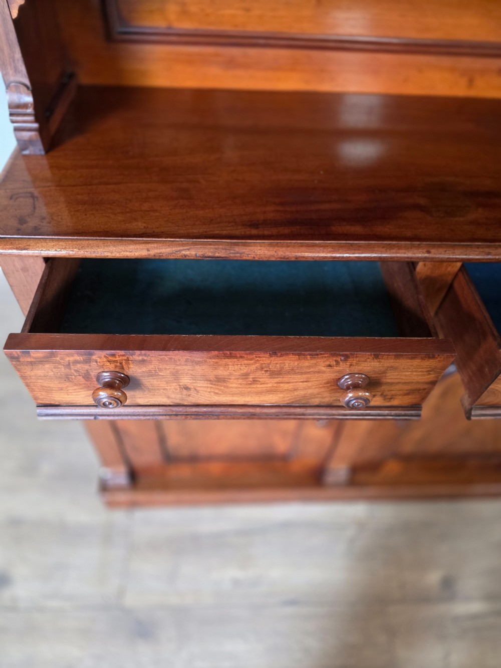 A Victorian mahogany glazed bookcase featuring a top spindle gallery, two glass cabinet doors, two drawers, and a lower double door cupboard on a plinth base. View XII