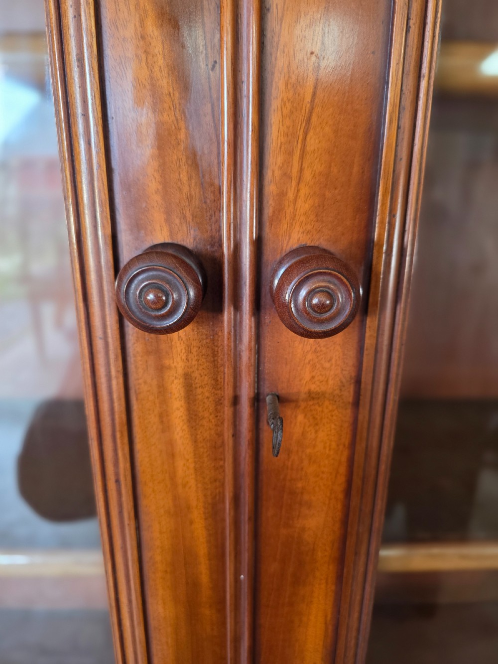 A Victorian mahogany glazed bookcase featuring a top spindle gallery, two glass cabinet doors, two drawers, and a lower double door cupboard on a plinth base. View XVII