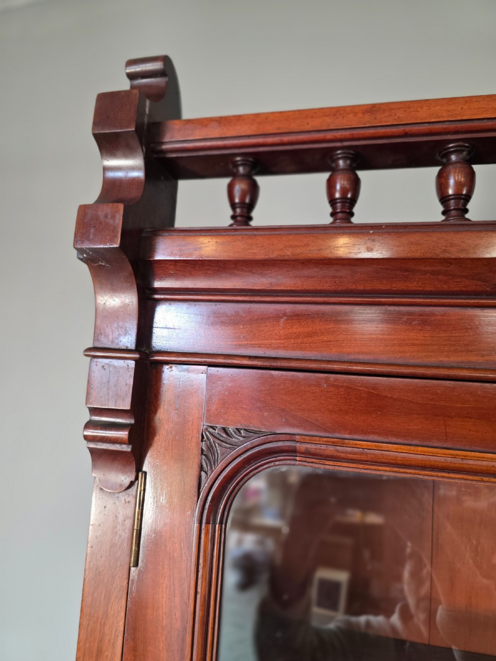 A Victorian mahogany glazed bookcase featuring a top spindle gallery, two glass cabinet doors, two drawers, and a lower double door cupboard on a plinth base. View XVIII