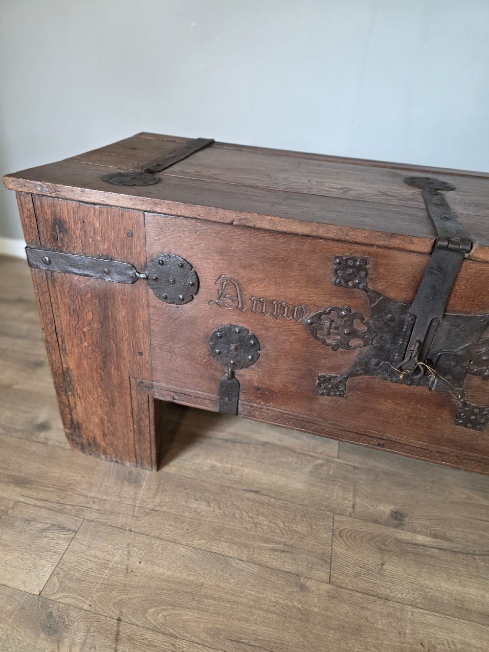 An 18th-century oak coffer featuring hand-forged wrought iron straps, a central escutcheon plate, and the carved inscription Anno 1743 on the front panel. View IV