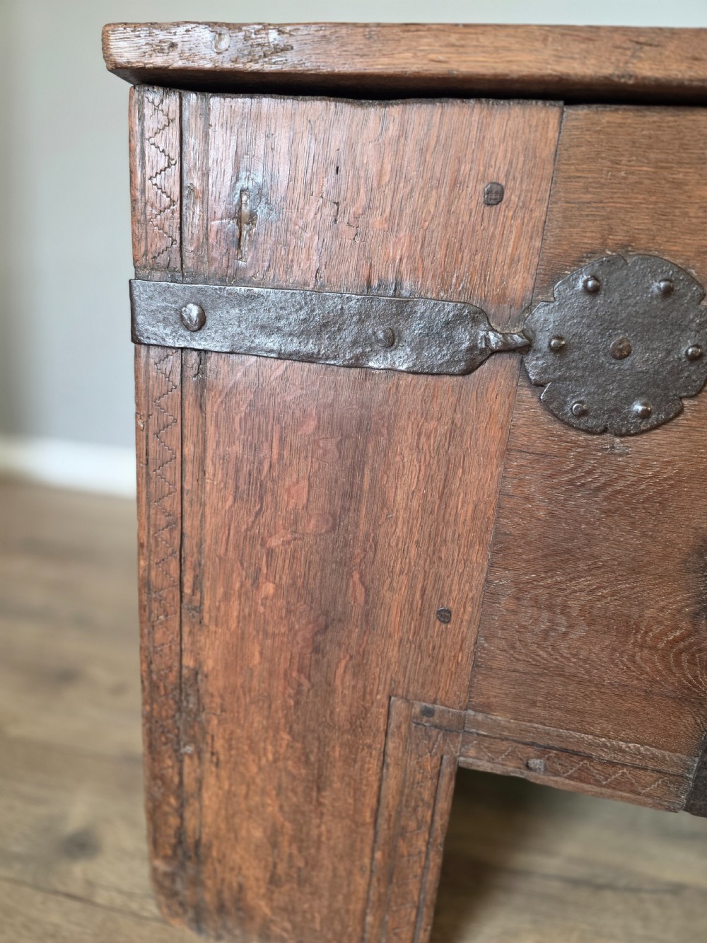 An 18th-century oak coffer featuring hand-forged wrought iron straps, a central escutcheon plate, and the carved inscription Anno 1743 on the front panel. View VI