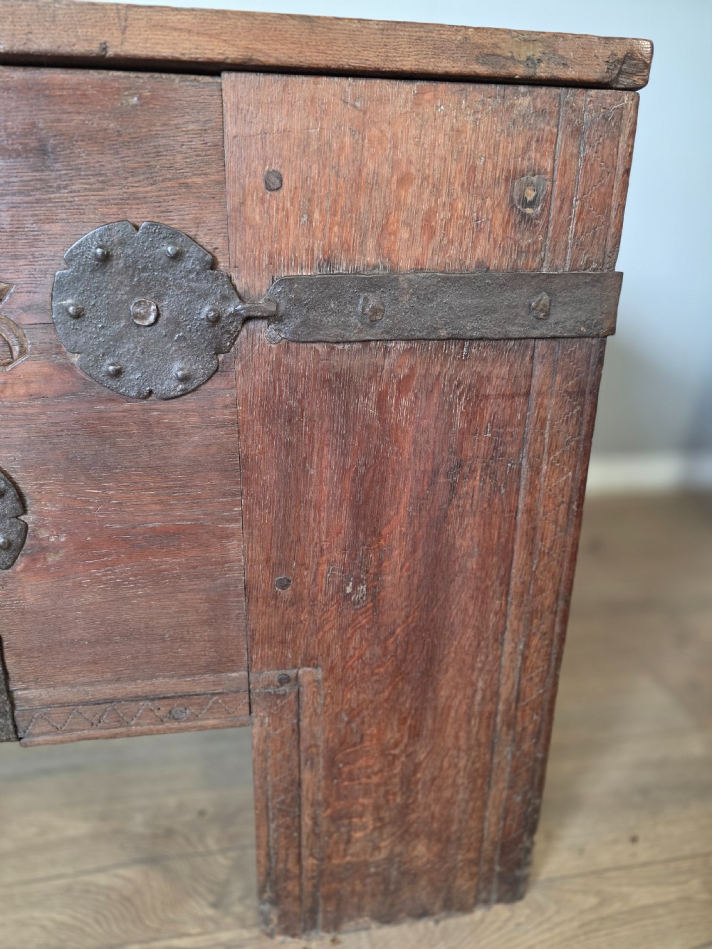 An 18th-century oak coffer featuring hand-forged wrought iron straps, a central escutcheon plate, and the carved inscription Anno 1743 on the front panel. View IX