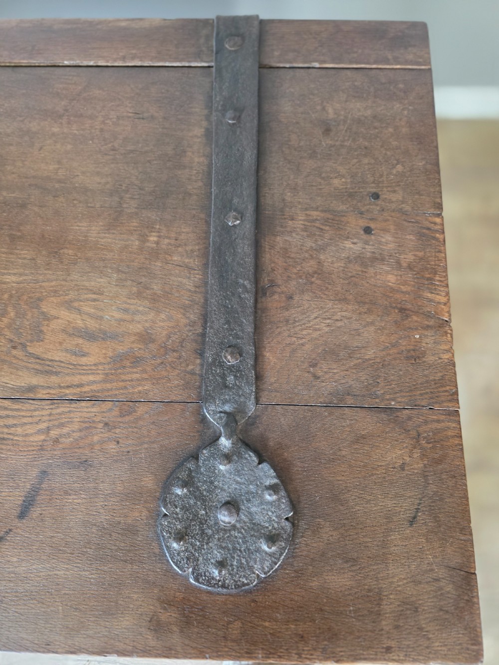 An 18th-century oak coffer featuring hand-forged wrought iron straps, a central escutcheon plate, and the carved inscription Anno 1743 on the front panel. View X