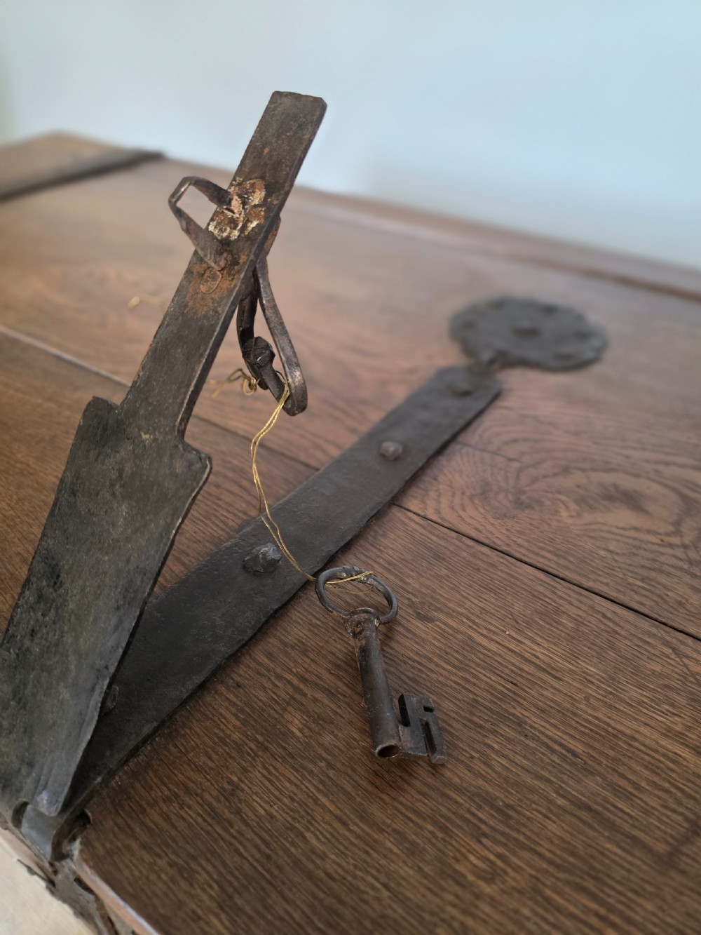 An 18th-century oak coffer featuring hand-forged wrought iron straps, a central escutcheon plate, and the carved inscription Anno 1743 on the front panel. View XI