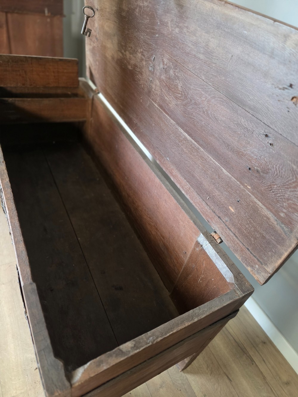 An 18th-century oak coffer featuring hand-forged wrought iron straps, a central escutcheon plate, and the carved inscription Anno 1743 on the front panel. View XV