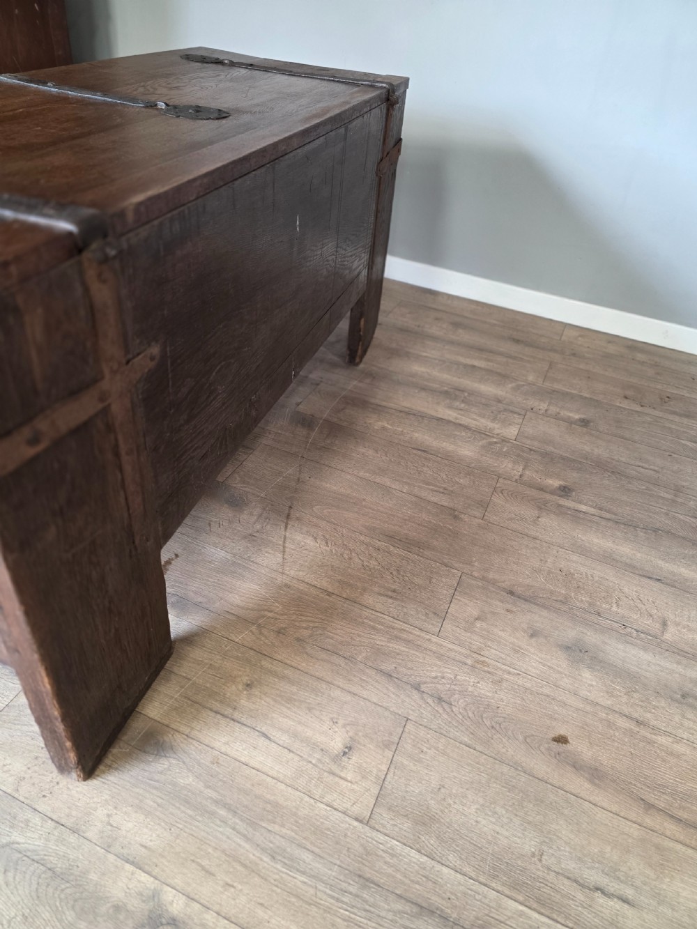 An 18th-century oak coffer featuring hand-forged wrought iron straps, a central escutcheon plate, and the carved inscription Anno 1743 on the front panel. View XVI
