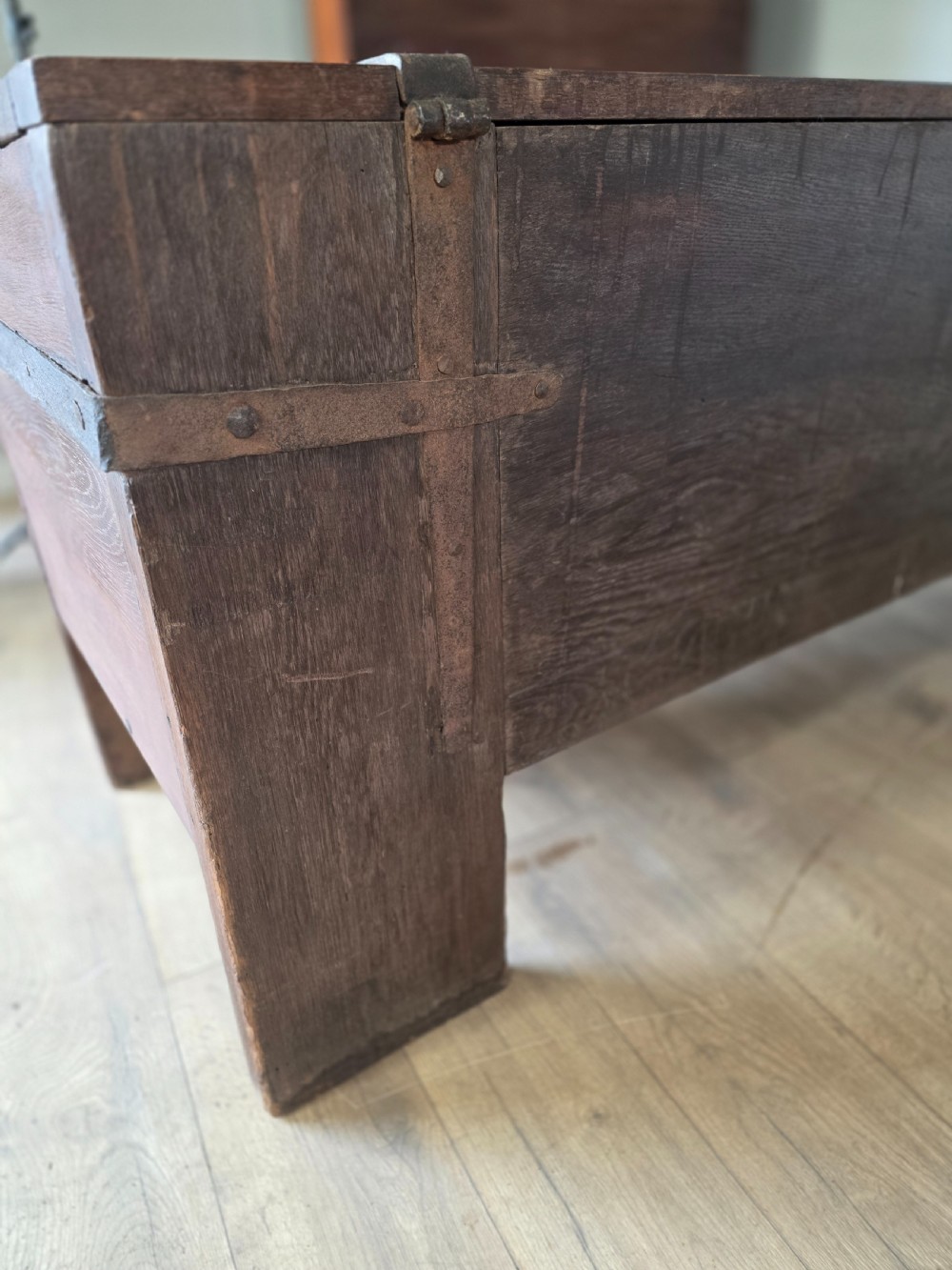 An 18th-century oak coffer featuring hand-forged wrought iron straps, a central escutcheon plate, and the carved inscription Anno 1743 on the front panel. View XVII