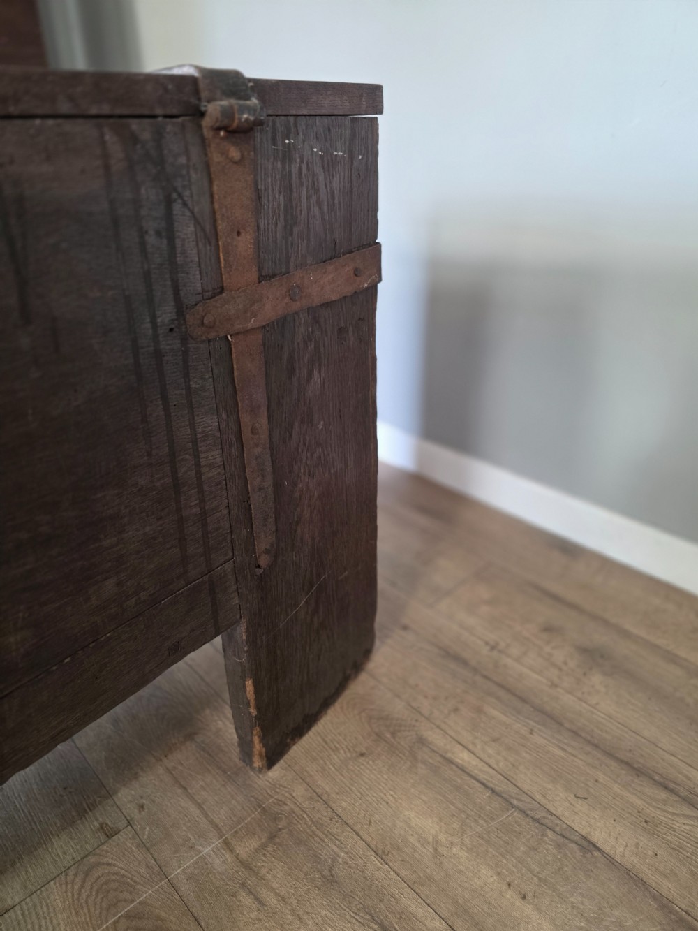 An 18th-century oak coffer featuring hand-forged wrought iron straps, a central escutcheon plate, and the carved inscription Anno 1743 on the front panel. View XVIII