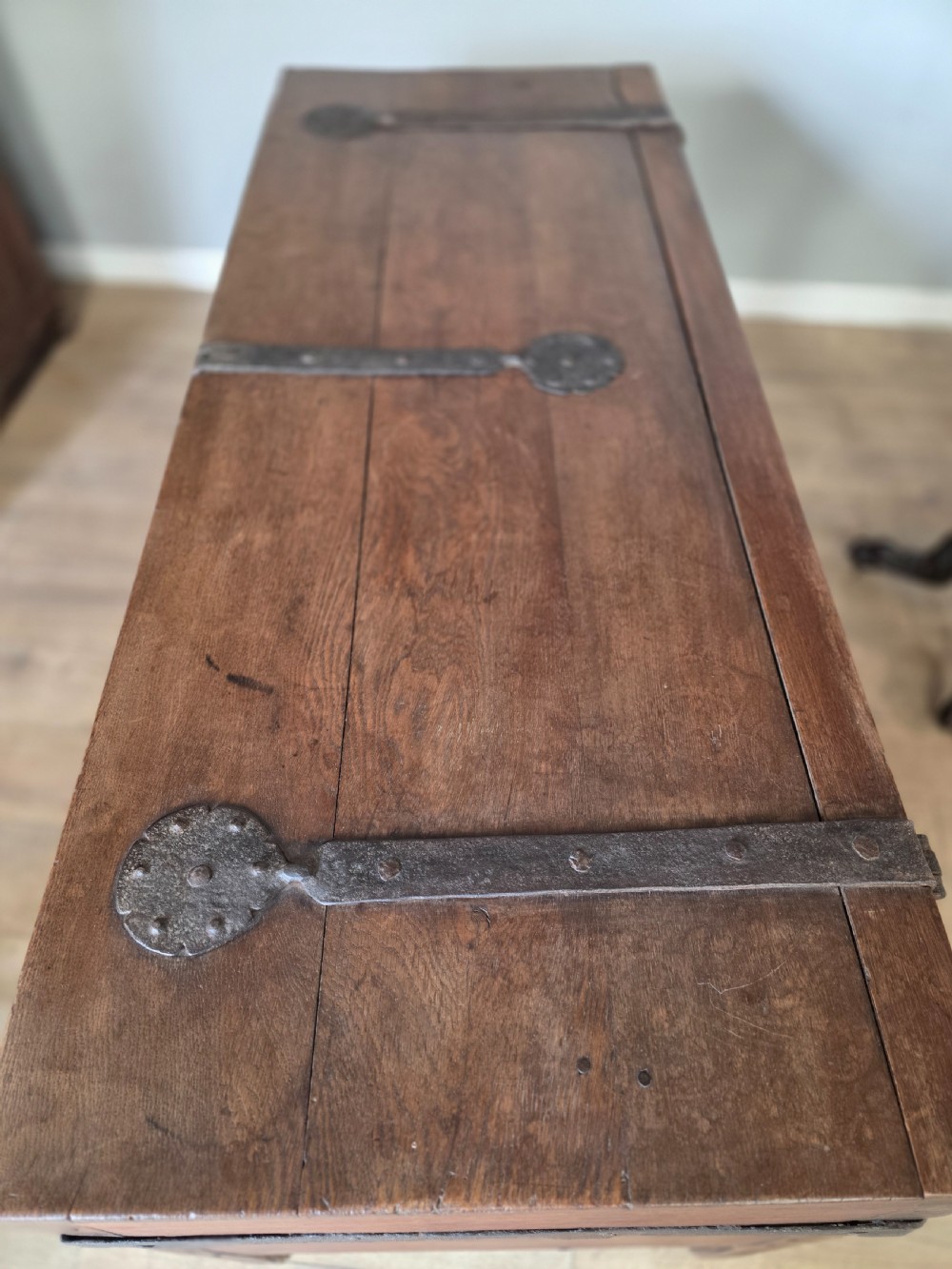 An 18th-century oak coffer featuring hand-forged wrought iron straps, a central escutcheon plate, and the carved inscription Anno 1743 on the front panel. View XX