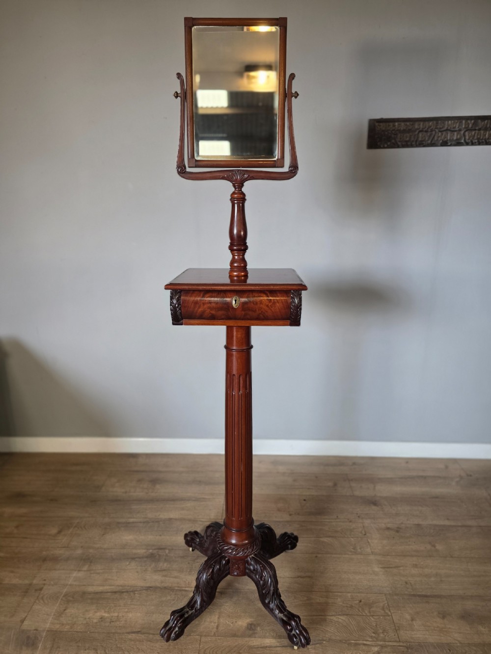A tall mahogany gentlemans shaving stand featuring an adjustable rectangular mirror, a single drawer pedestal, a fluted column, and a carved tripod base. View II