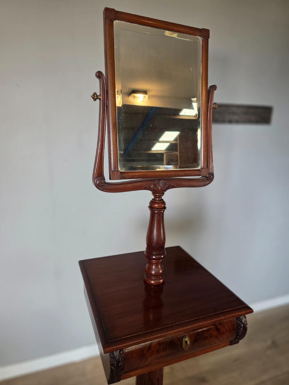 A tall mahogany gentlemans shaving stand featuring an adjustable rectangular mirror, a single drawer pedestal, a fluted column, and a carved tripod base. View IX
