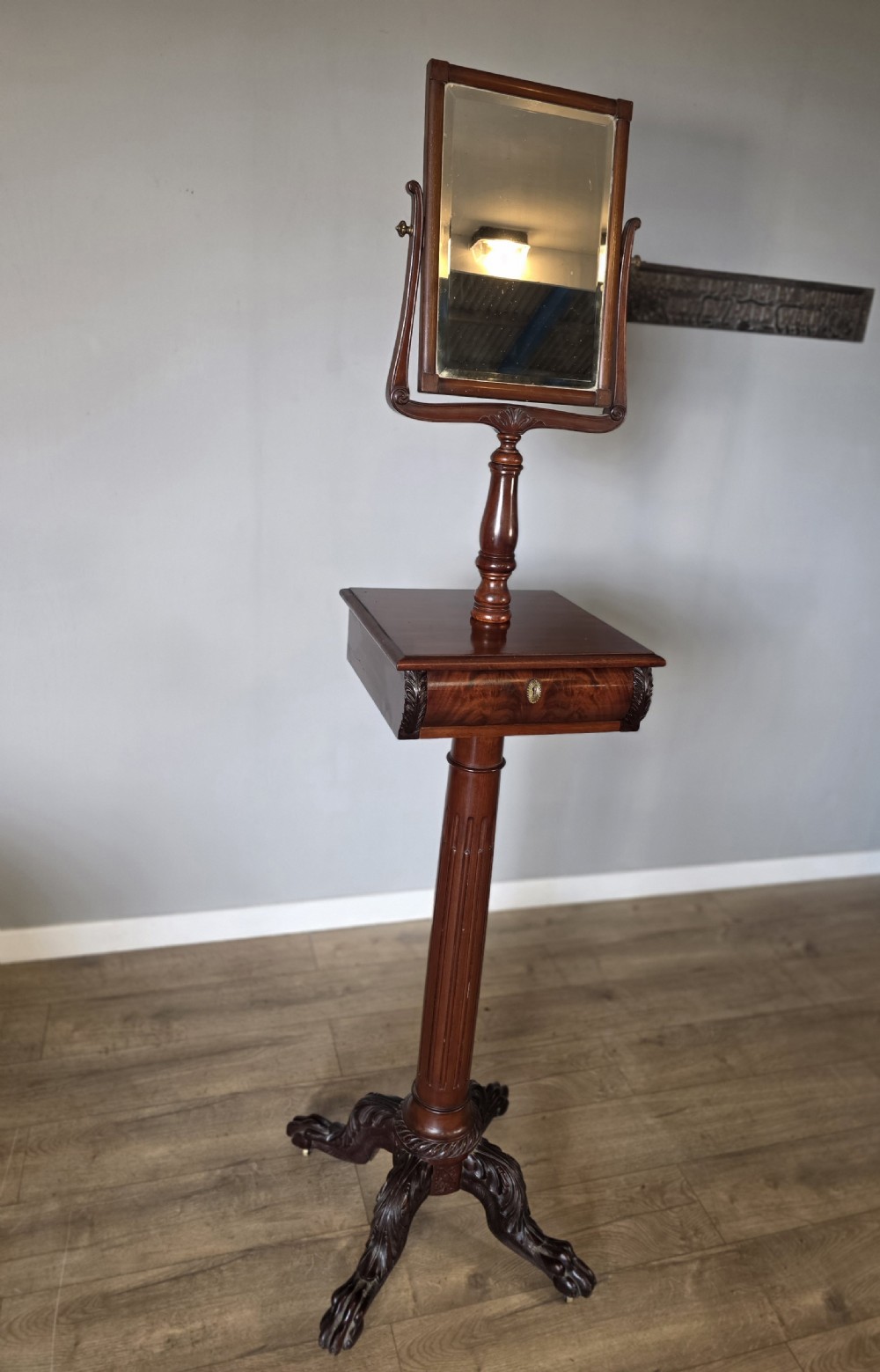 A tall mahogany gentlemans shaving stand featuring an adjustable rectangular mirror, a single drawer pedestal, a fluted column, and a carved tripod base. View XII