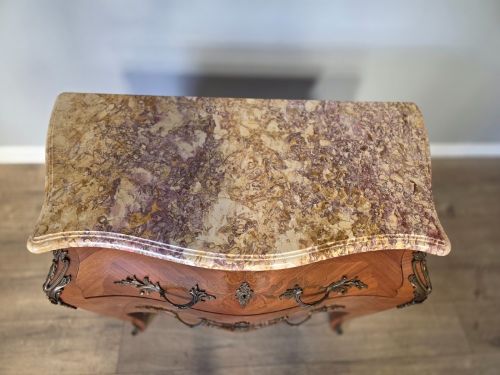 A French Rococo style bombe commode featuring a shaped marble top, floral marquetry veneer, two drawers, and ornamental gilt bronze mounts. View VII