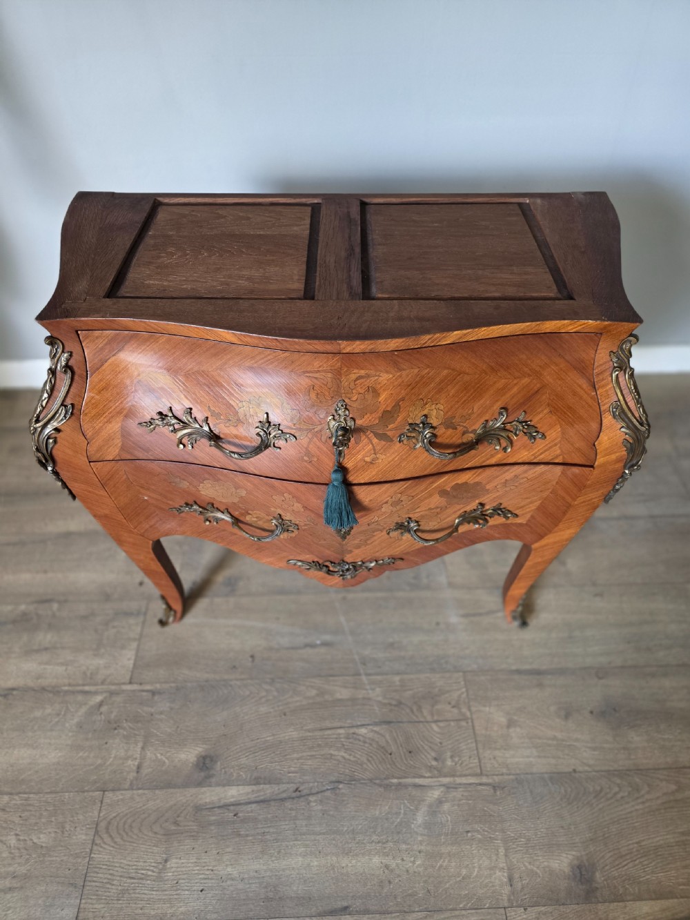 A French Rococo style bombe commode featuring a shaped marble top, floral marquetry veneer, two drawers, and ornamental gilt bronze mounts. View XVI