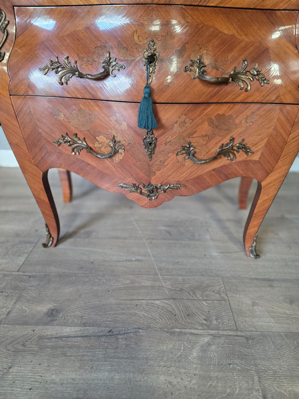 A French Rococo style bombe commode featuring a shaped marble top, floral marquetry veneer, two drawers, and ornamental gilt bronze mounts. View XVIII