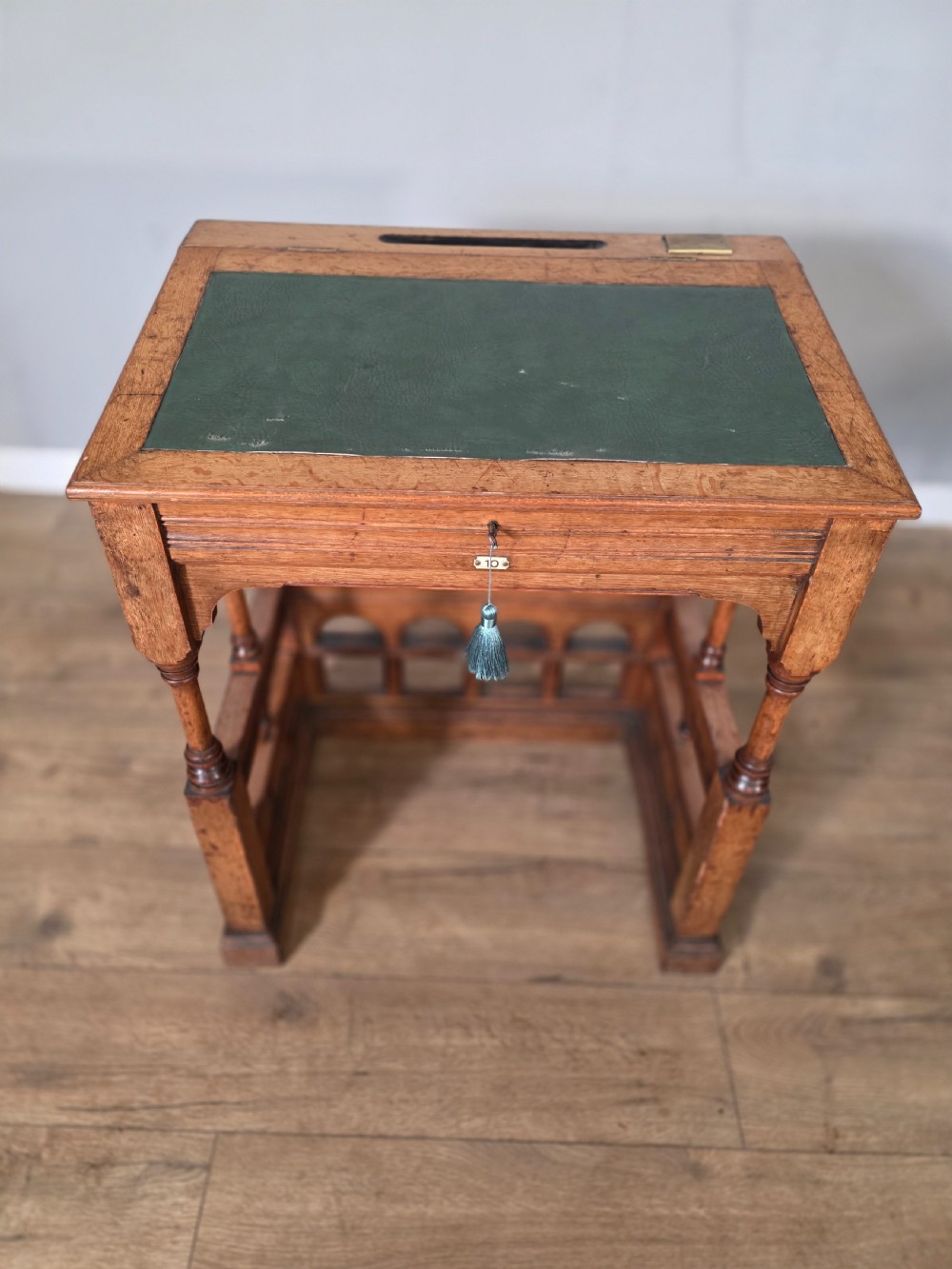 A late Victorian oak clerks desk with an inset green leather writing top, turned legs, and an arcaded lower framework. View II