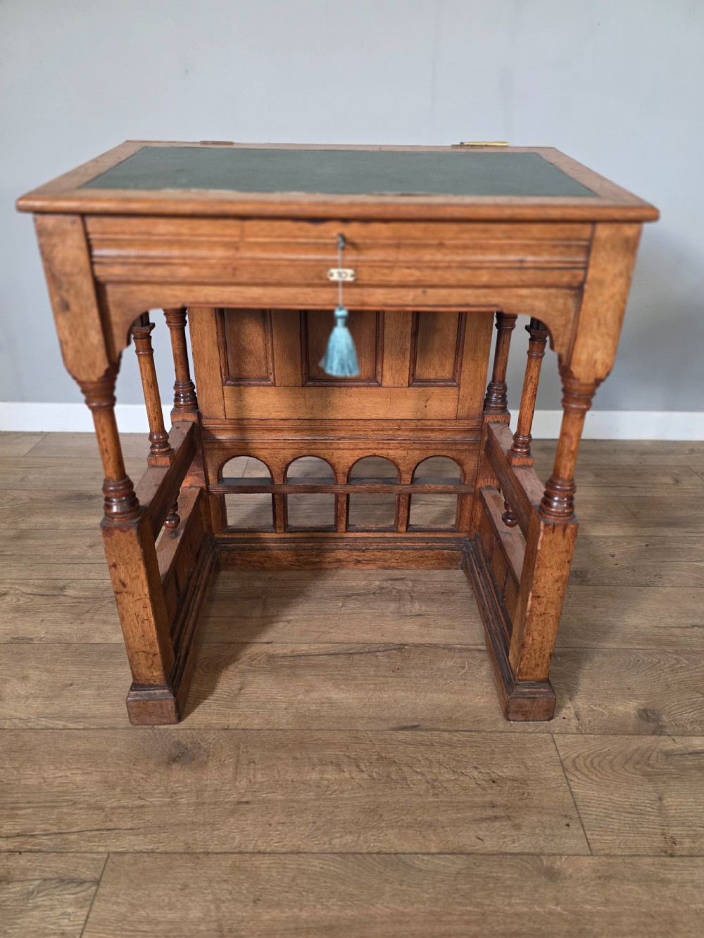 A late Victorian oak clerks desk with an inset green leather writing top, turned legs, and an arcaded lower framework. View III