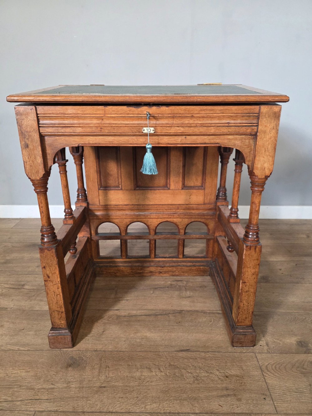 A late Victorian oak clerks desk with an inset green leather writing top, turned legs, and an arcaded lower framework. View IX