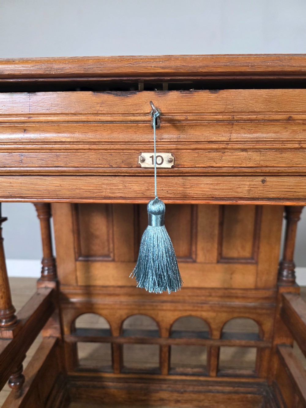 A late Victorian oak clerks desk with an inset green leather writing top, turned legs, and an arcaded lower framework. View X