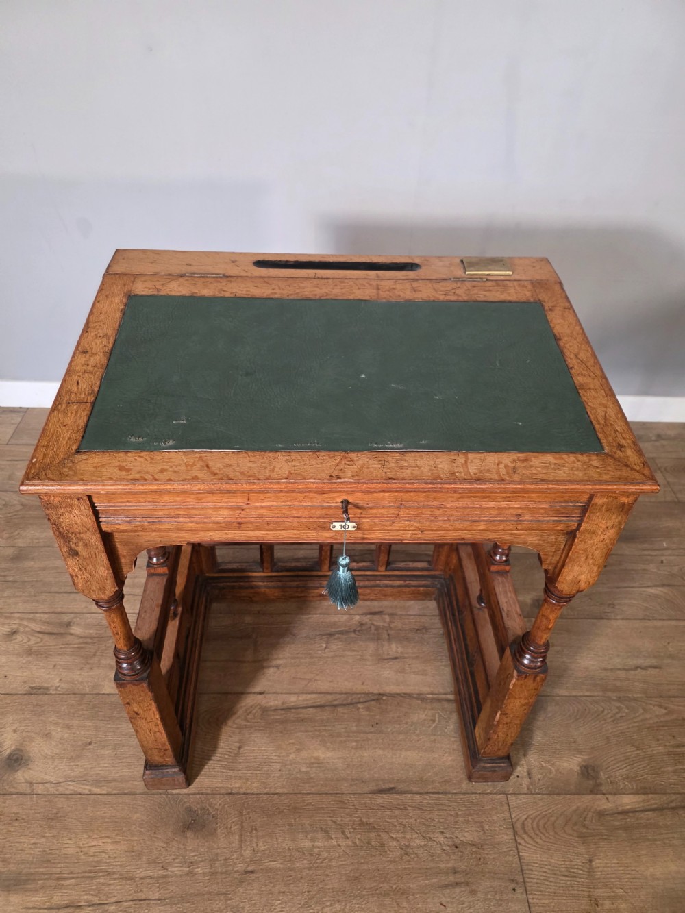 A late Victorian oak clerks desk with an inset green leather writing top, turned legs, and an arcaded lower framework. View XII