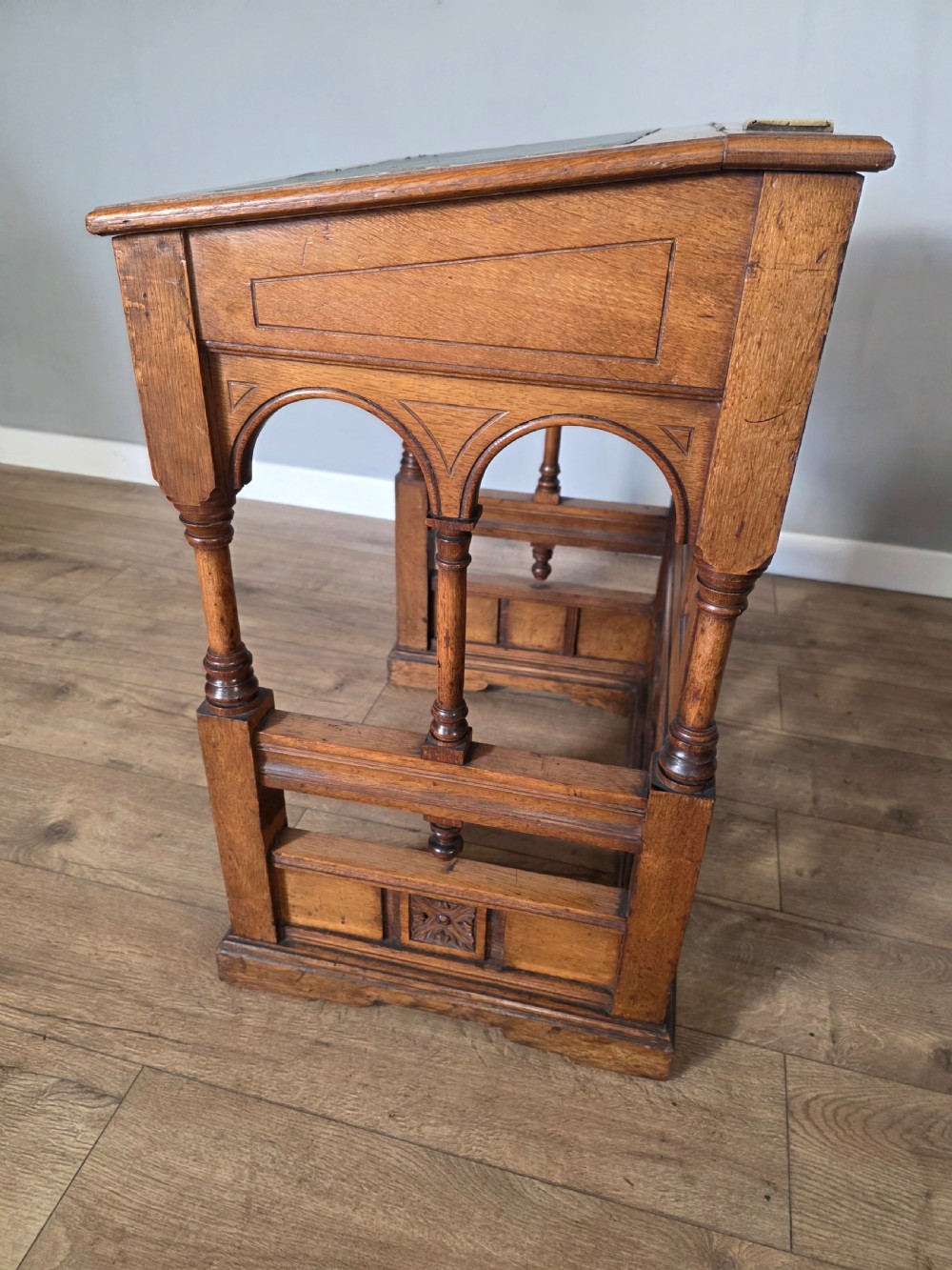 A late Victorian oak clerks desk with an inset green leather writing top, turned legs, and an arcaded lower framework. View XVII