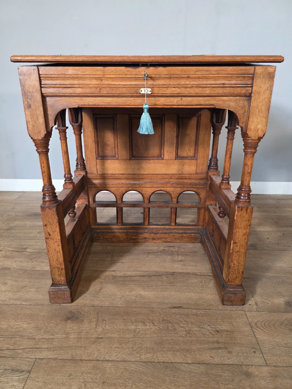 A late Victorian oak clerks desk with an inset green leather writing top, turned legs, and an arcaded lower framework. View XIX