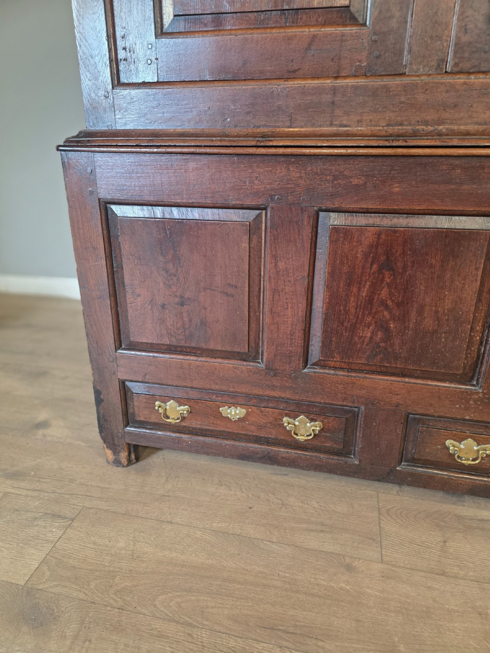 A dark oak two-tier antique cupboard with arched panel double doors above a base with recessed panels and two drawers. View IV