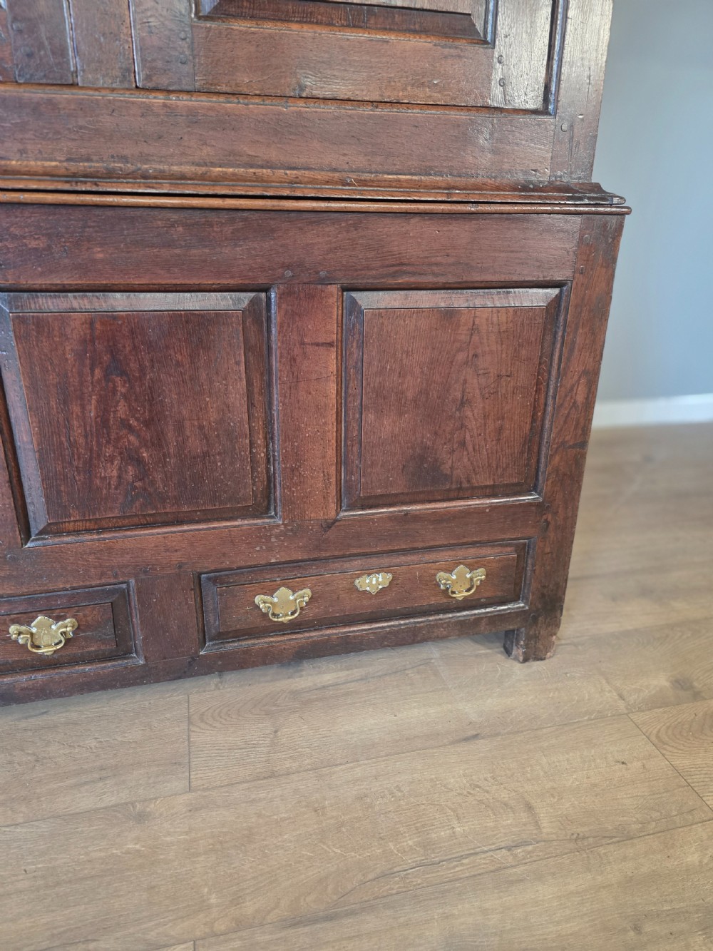 A dark oak two-tier antique cupboard with arched panel double doors above a base with recessed panels and two drawers. View V