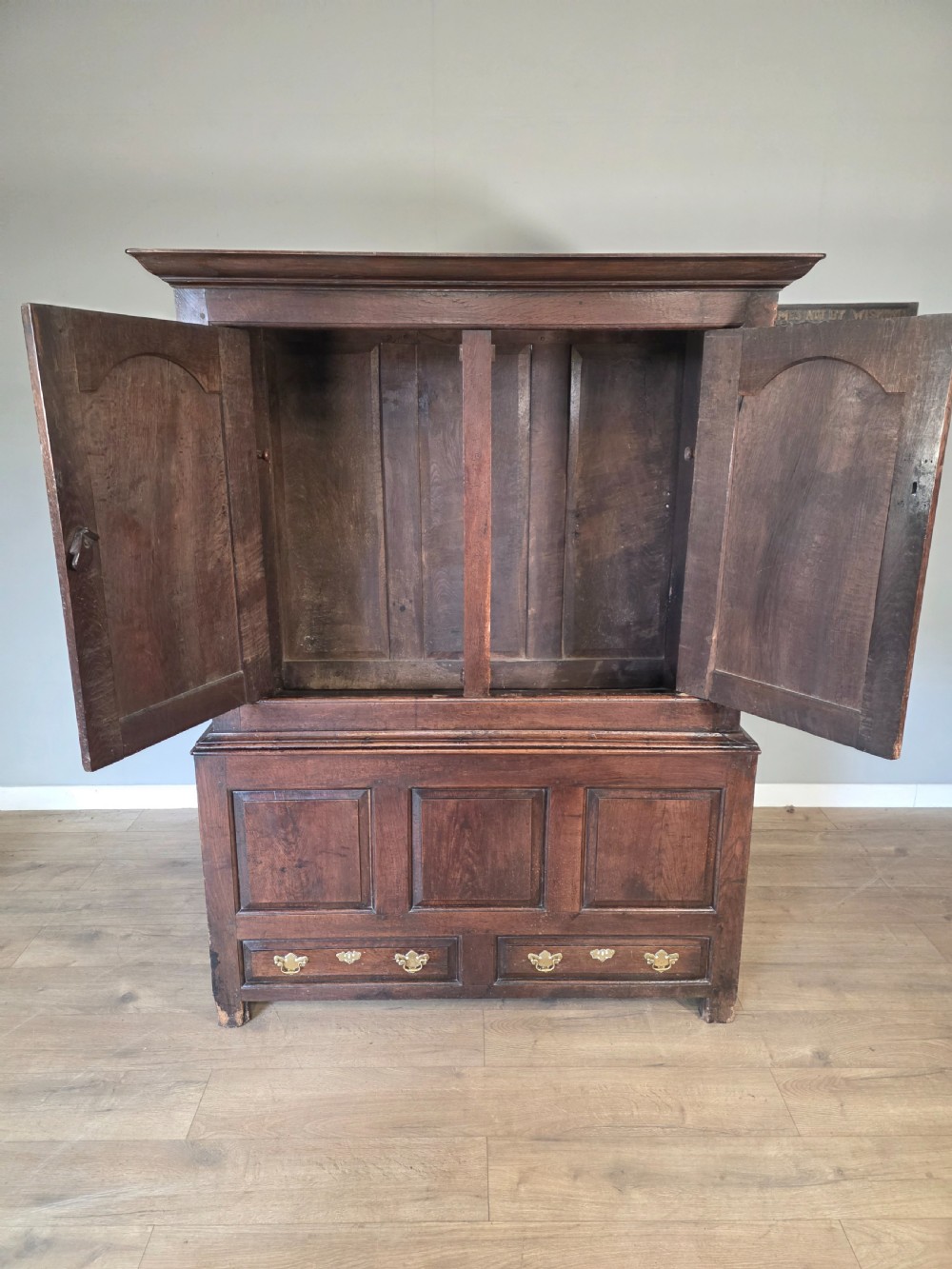 A dark oak two-tier antique cupboard with arched panel double doors above a base with recessed panels and two drawers. View VIII