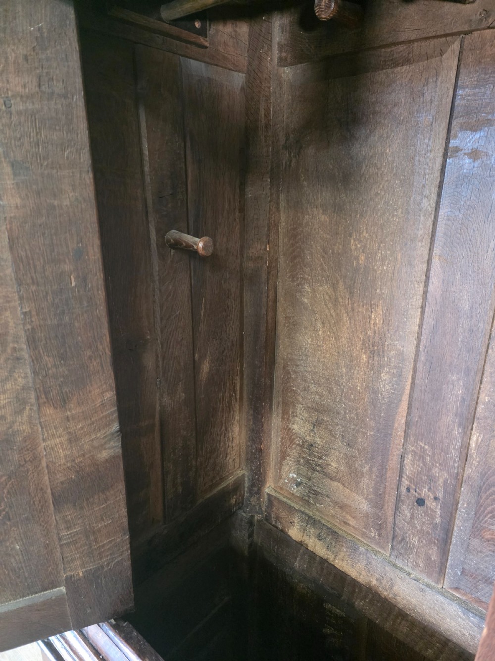 A dark oak two-tier antique cupboard with arched panel double doors above a base with recessed panels and two drawers. View IX