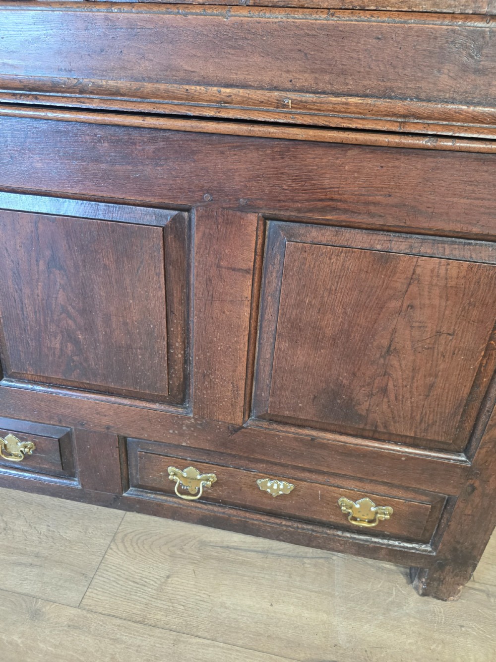 A dark oak two-tier antique cupboard with arched panel double doors above a base with recessed panels and two drawers. View XV