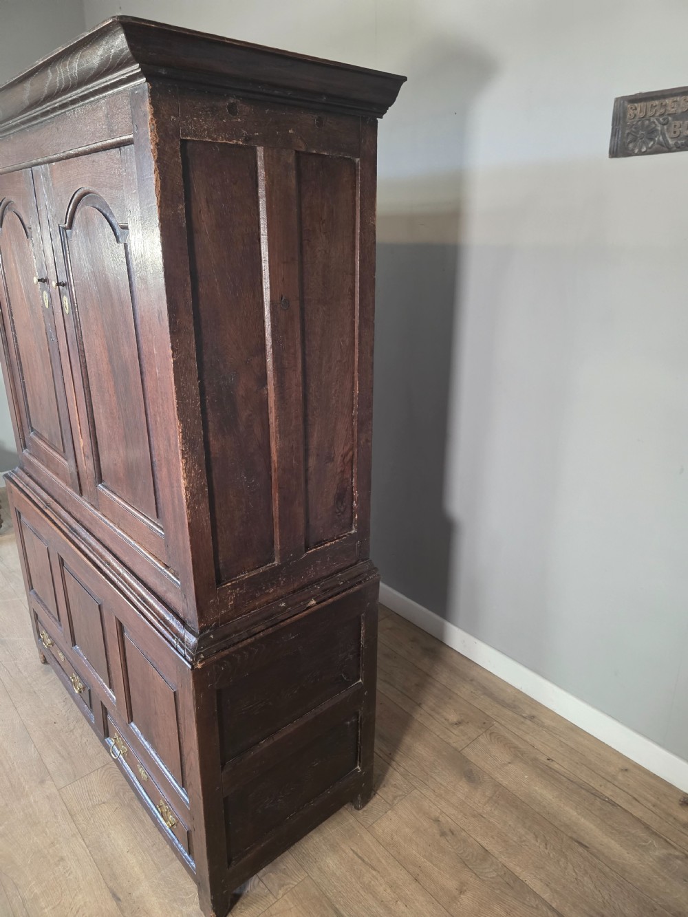 A dark oak two-tier antique cupboard with arched panel double doors above a base with recessed panels and two drawers. View XVI