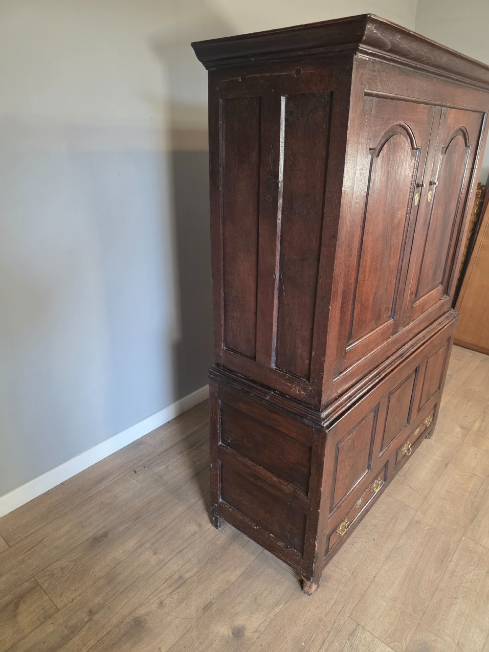 A dark oak two-tier antique cupboard with arched panel double doors above a base with recessed panels and two drawers. View XVIII