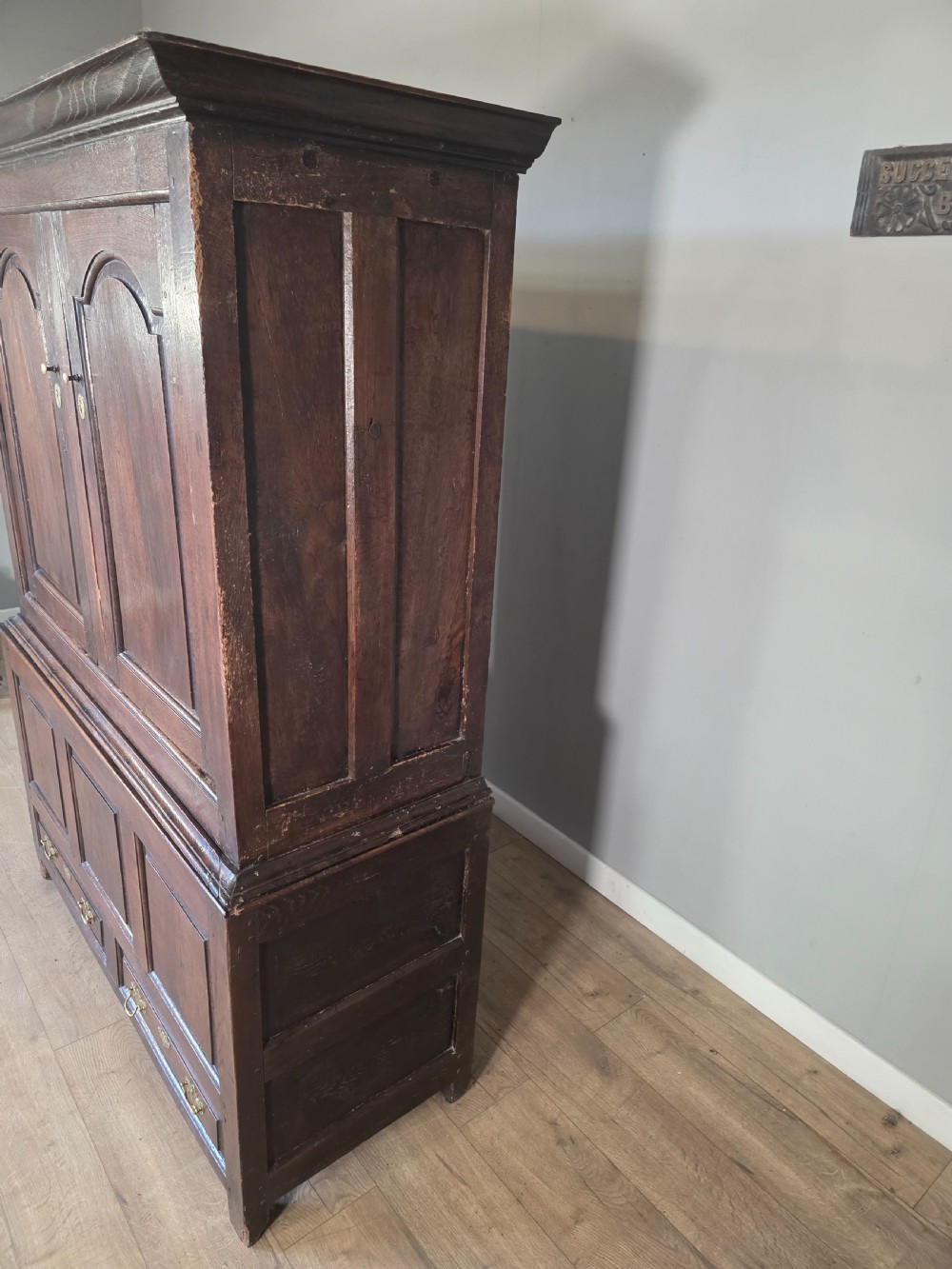 A dark oak two-tier antique cupboard with arched panel double doors above a base with recessed panels and two drawers. View XIX